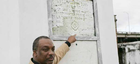 man points to tomb marker